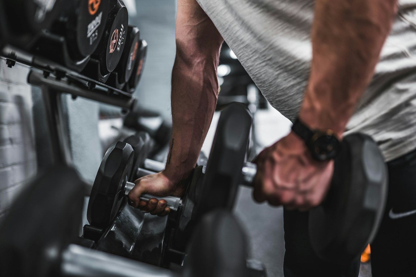 A person lifting dumbbells from a rack