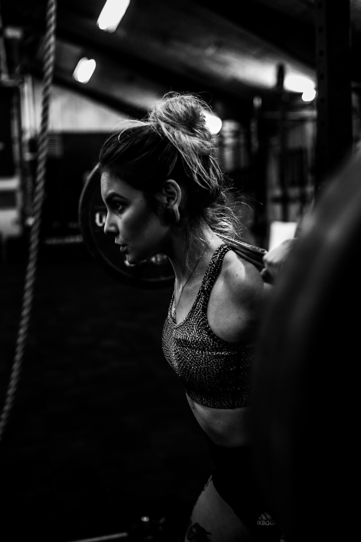 A person set up for a barbell squat, with a spotter beside them