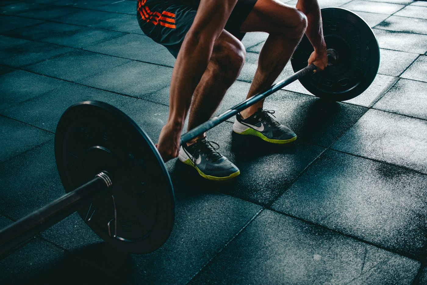 A person gripping a loaded barbell in a gym